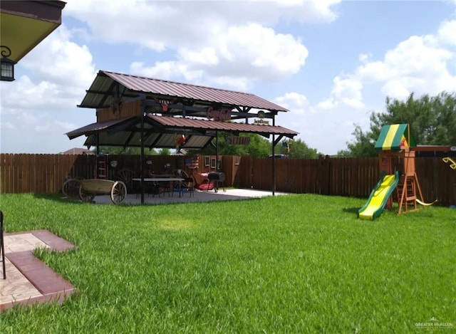 view of yard featuring a patio area, a playground, and fence