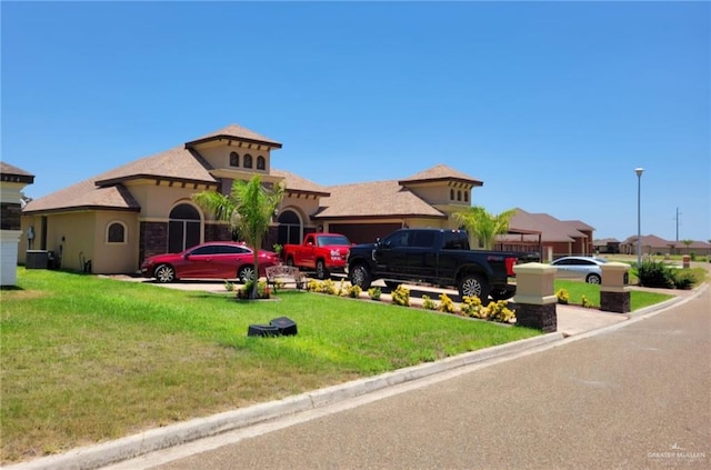 view of front of property with a garage, cooling unit, and a front yard