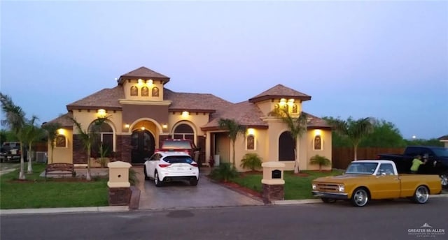 view of front of house featuring stucco siding, driveway, and a front lawn