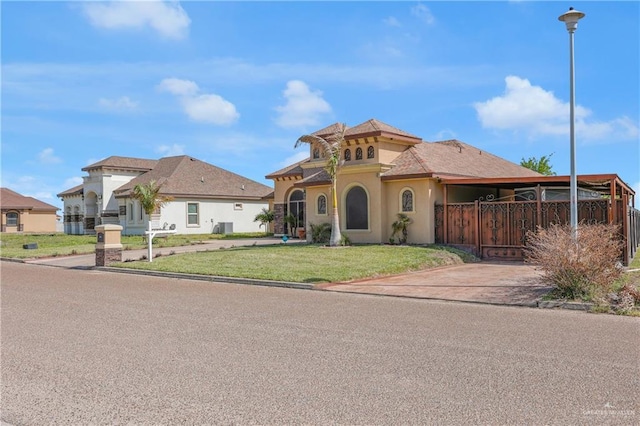 view of front of home with a front yard, stucco siding, fence, and central air condition unit