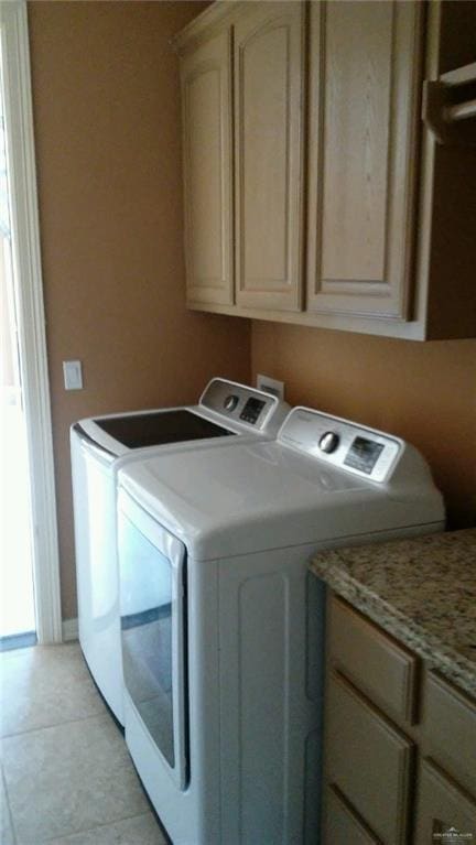 laundry area with light tile patterned floors, cabinet space, and separate washer and dryer