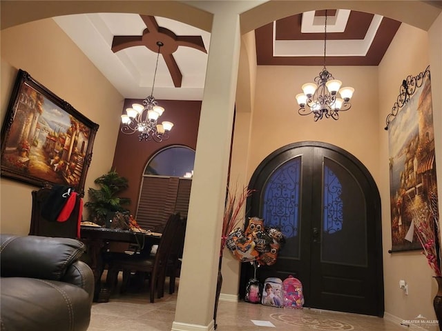 entrance foyer with a notable chandelier, a raised ceiling, french doors, arched walkways, and baseboards