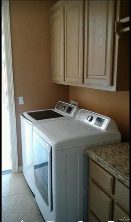 washroom featuring light tile patterned flooring, cabinet space, baseboards, and washing machine and clothes dryer