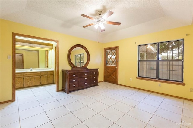 unfurnished bedroom with vaulted ceiling, ceiling fan, a tray ceiling, and light tile patterned floors