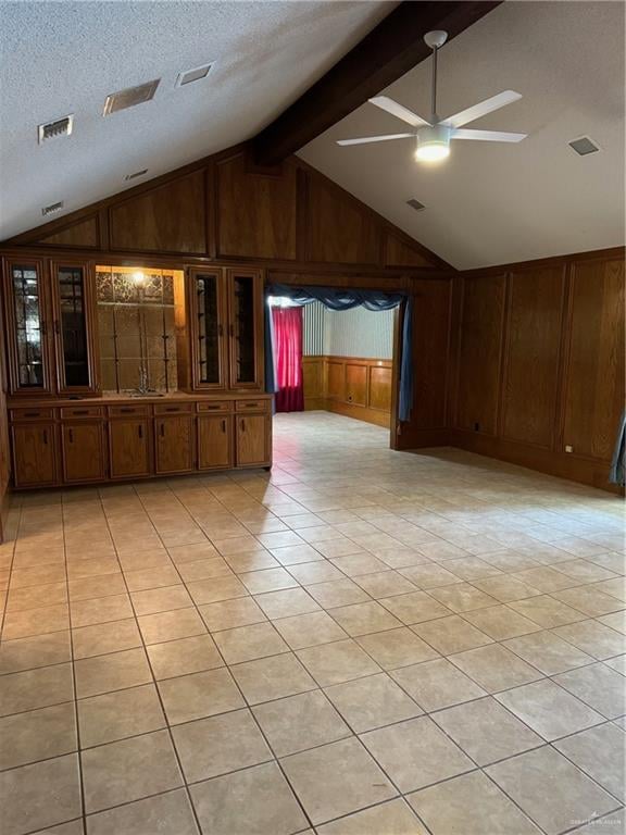 tiled spare room with ceiling fan, wood walls, a textured ceiling, and vaulted ceiling with beams