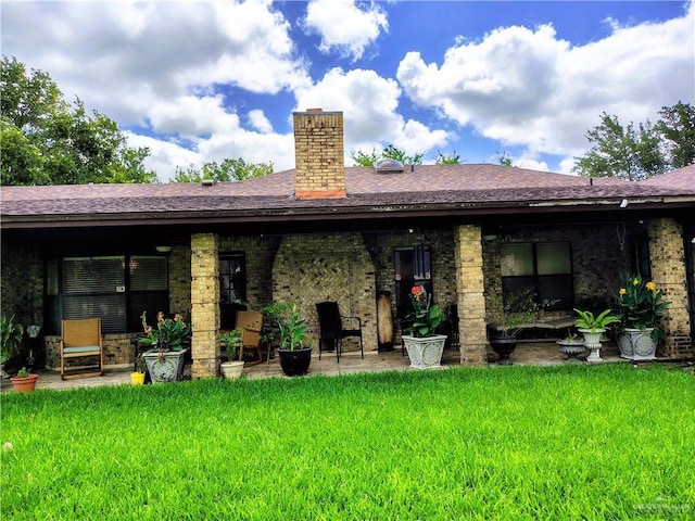 702 Clifford Dr, Weslaco, TX 78596 - rear view of house featuring a yard, a chimney, a patio, and brick siding