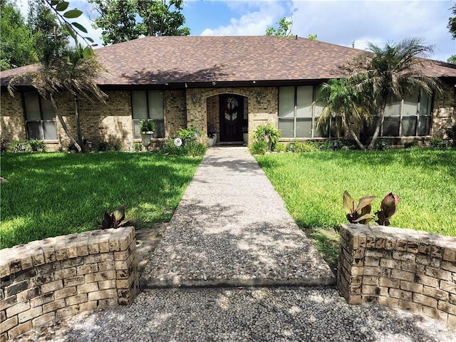 702 Clifford Dr, Weslaco, TX 78596 - view of front facade with a front yard, a shingled roof, and brick siding