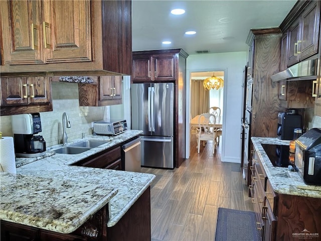 702 Clifford Dr, Weslaco, TX 78596 - kitchen with appliances with stainless steel finishes, a chandelier, tasteful backsplash, under cabinet range hood, and light stone counters