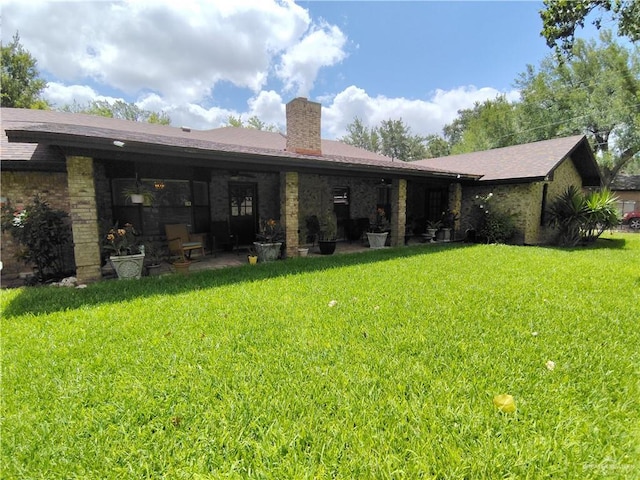702 Clifford Dr, Weslaco, TX 78596 - rear view of house featuring a chimney, a lawn, and brick siding