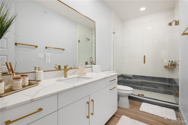 bathroom featuring hardwood / wood-style floors, vanity, toilet, and a shower with shower door