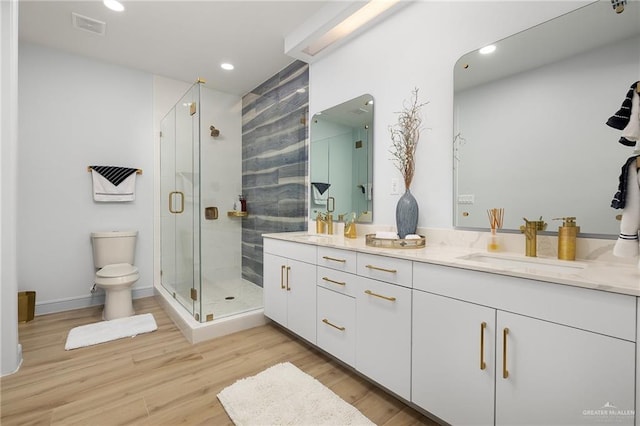 bathroom featuring toilet, vanity, an enclosed shower, and hardwood / wood-style flooring