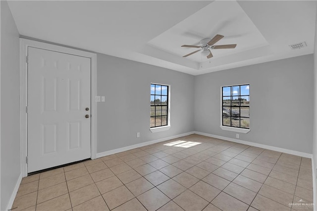 interior space featuring light tile patterned floors, a raised ceiling, and ceiling fan