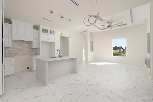 1921 Lime St, San Juan, TX 78589 - kitchen with open floor plan, ceiling fan, a kitchen island with sink, decorative backsplash, and white cabinetry