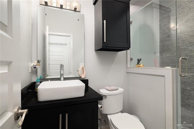 bathroom with a shower with door, vanity, and toilet