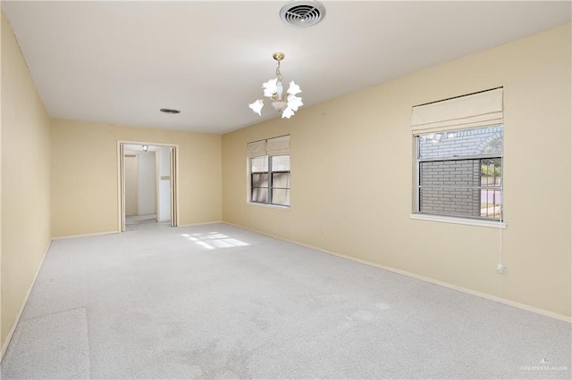 empty room featuring carpet and a notable chandelier