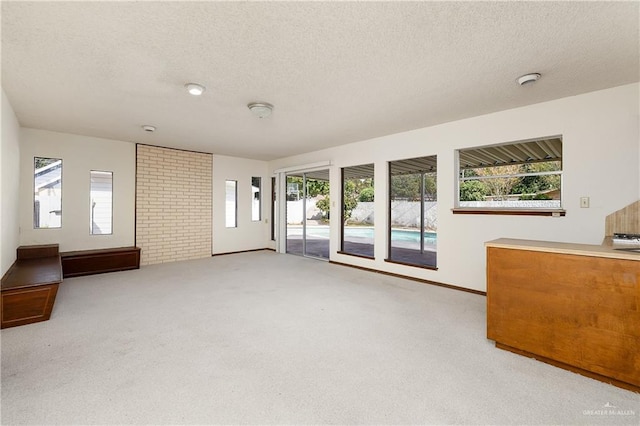 unfurnished living room with light carpet and a textured ceiling