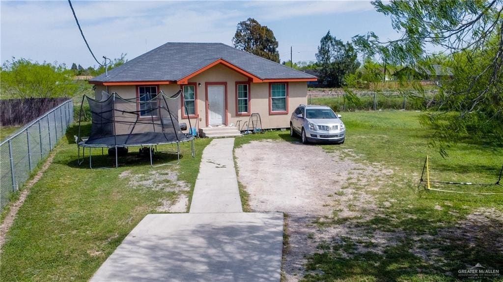 bungalow featuring a front yard and a trampoline