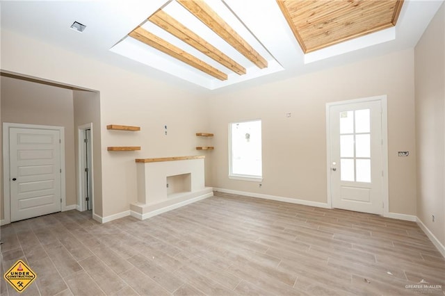 unfurnished living room featuring a skylight and light hardwood / wood-style flooring