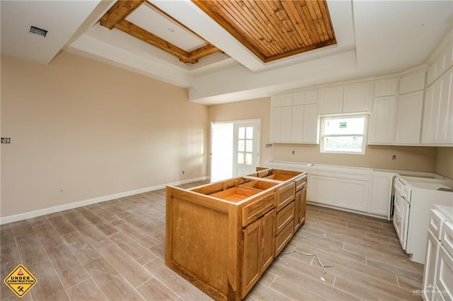 kitchen with a tray ceiling, a kitchen island, and white cabinets