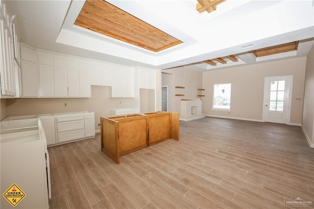 kitchen with a tray ceiling, white cabinetry, and light wood-type flooring