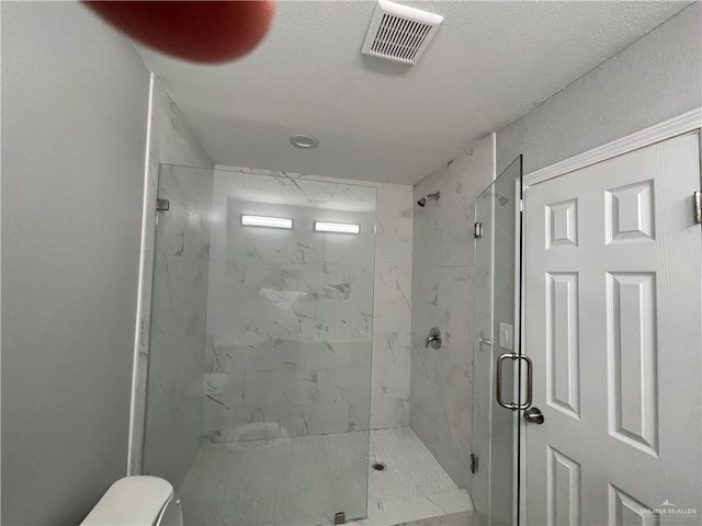 bathroom with a shower with door, a textured ceiling, and toilet