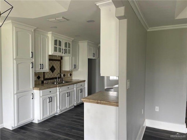 kitchen featuring decorative backsplash, crown molding, dark wood-type flooring, sink, and white cabinets