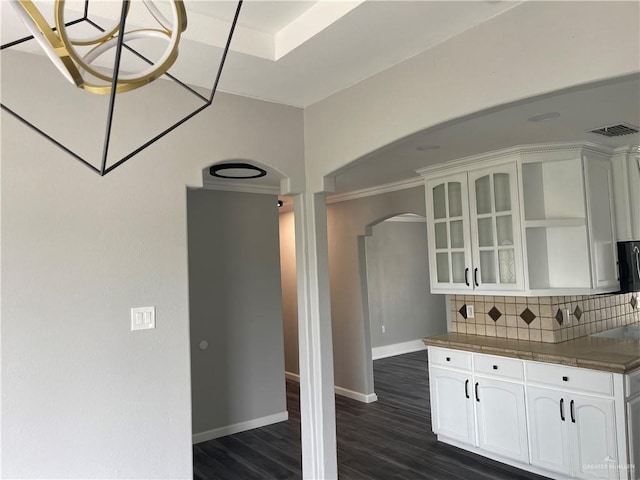 kitchen with backsplash, dark hardwood / wood-style floors, white cabinetry, and crown molding