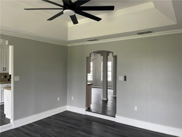 unfurnished room with dark hardwood / wood-style floors, ceiling fan, crown molding, and a tray ceiling