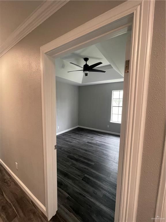 spare room with crown molding, ceiling fan, and dark wood-type flooring