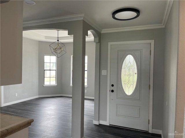 foyer entrance featuring crown molding, dark wood-type flooring, and an inviting chandelier