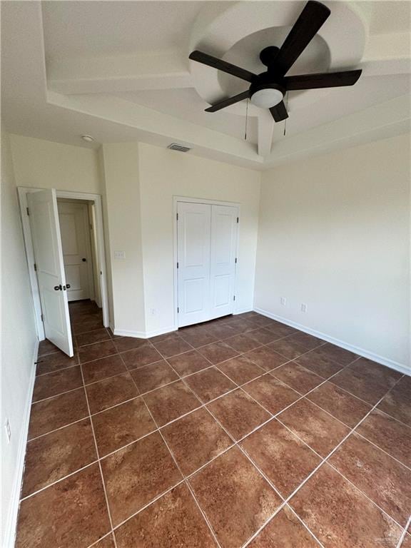 unfurnished bedroom with a closet, dark tile patterned flooring, and ceiling fan