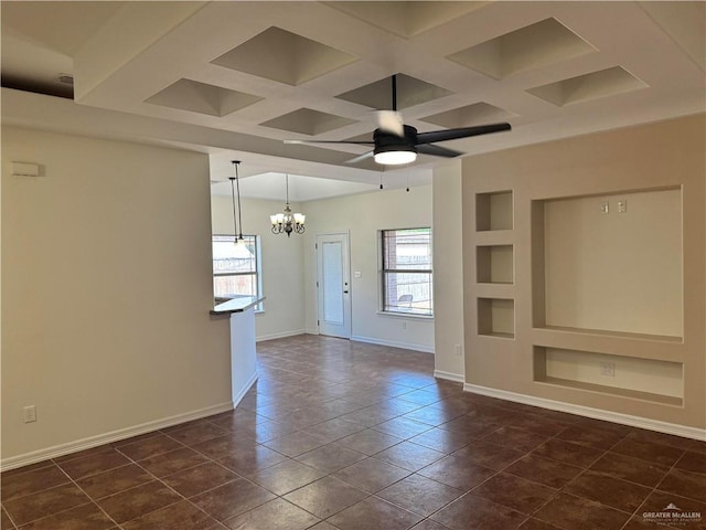 unfurnished living room with built in features, dark tile patterned floors, ceiling fan with notable chandelier, and coffered ceiling