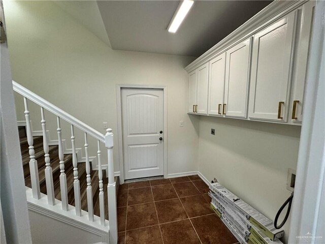 laundry area with electric dryer hookup, cabinets, and dark tile patterned floors