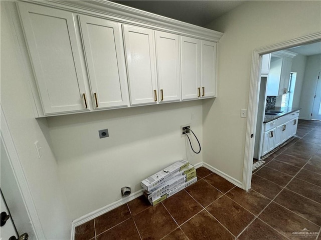 clothes washing area with cabinets, dark tile patterned flooring, sink, hookup for a washing machine, and hookup for an electric dryer