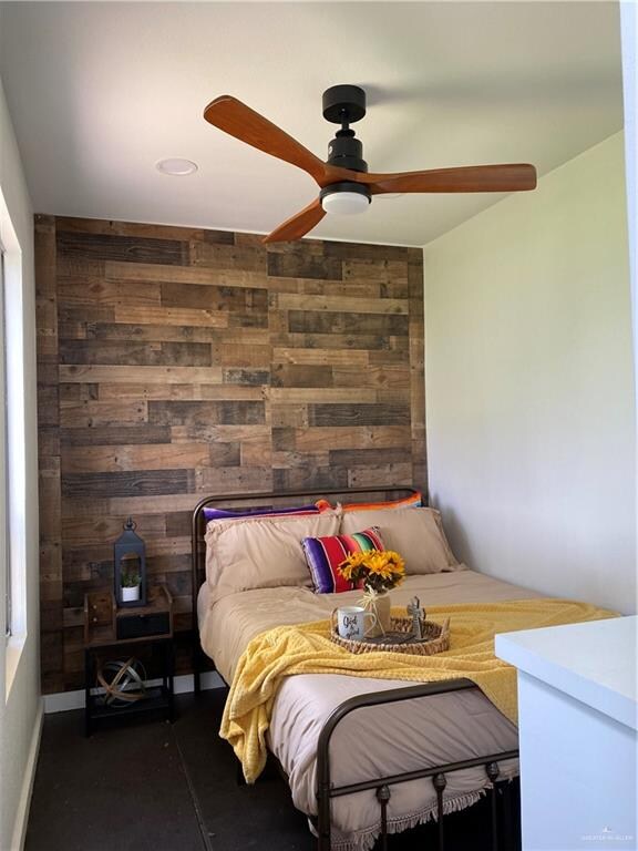 bedroom featuring ceiling fan and wooden walls