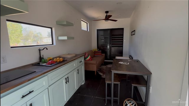 kitchen featuring ceiling fan, dark tile patterned floors, and white cabinetry