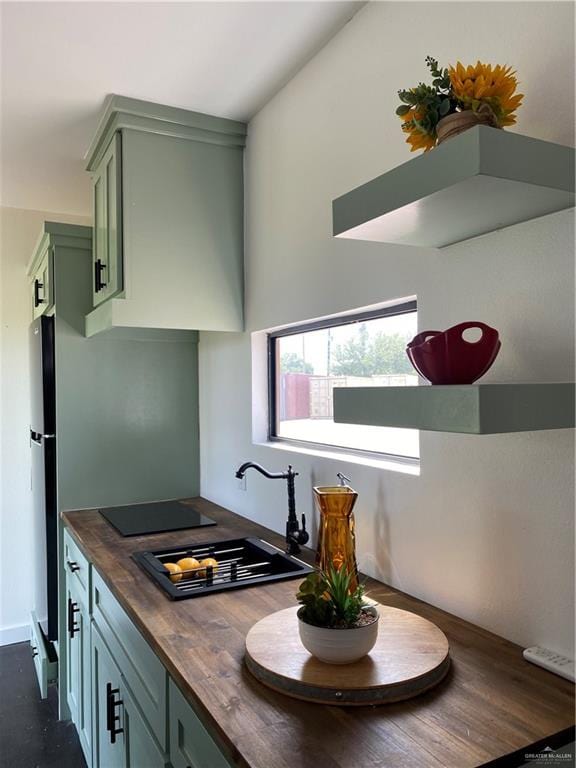 kitchen with wood counters, dark hardwood / wood-style flooring, black electric cooktop, sink, and green cabinetry