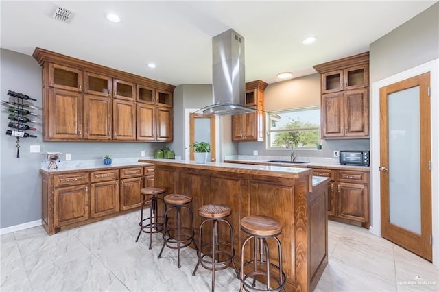 kitchen featuring a center island, a kitchen breakfast bar, island range hood, and sink