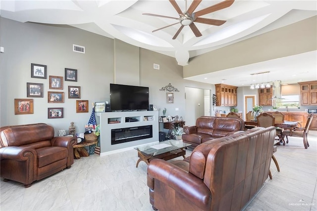 living room featuring ceiling fan, a towering ceiling, and sink