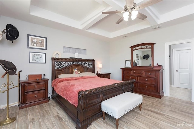 bedroom featuring beamed ceiling, light hardwood / wood-style floors, a raised ceiling, and ceiling fan