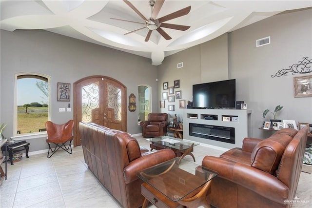 living room featuring ceiling fan, light tile patterned floors, and a towering ceiling