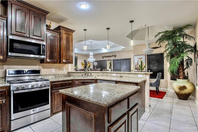 kitchen featuring sink, stainless steel appliances, kitchen peninsula, pendant lighting, and a kitchen island