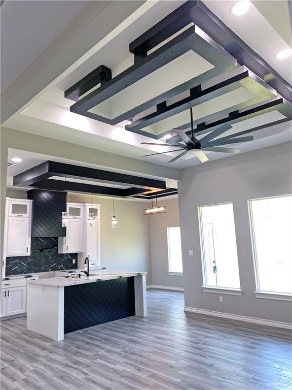 kitchen featuring a healthy amount of sunlight, light hardwood / wood-style flooring, white cabinets, and hanging light fixtures