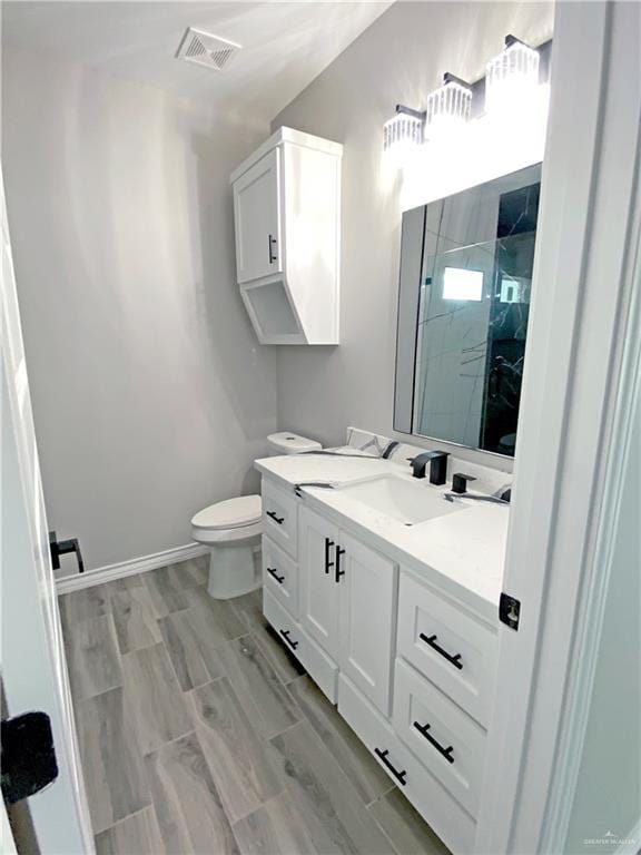 bathroom with toilet, vanity, wood-type flooring, and walk in shower