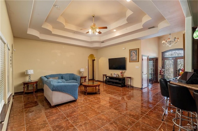 living room with french doors, ceiling fan with notable chandelier, and a raised ceiling