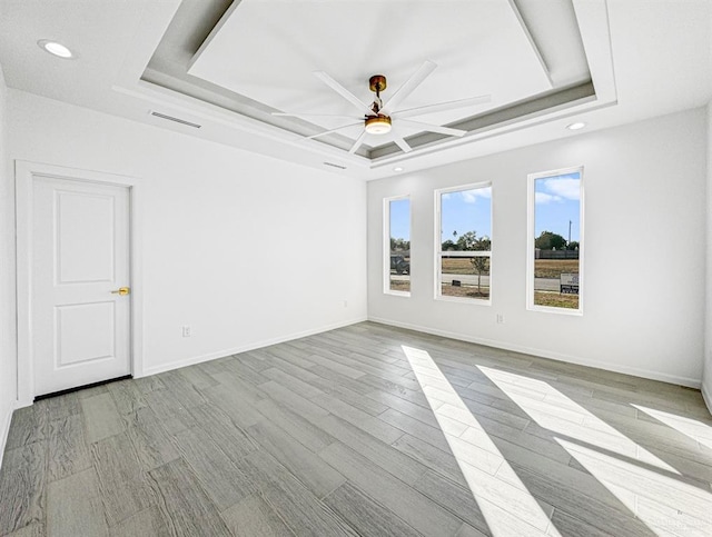 spare room featuring a tray ceiling, visible vents, ceiling fan, and baseboards