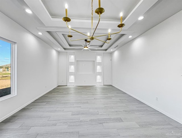 empty room with a tray ceiling, light wood-type flooring, recessed lighting, and baseboards