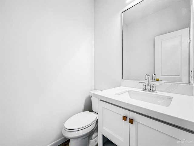 bathroom featuring toilet, baseboards, and vanity