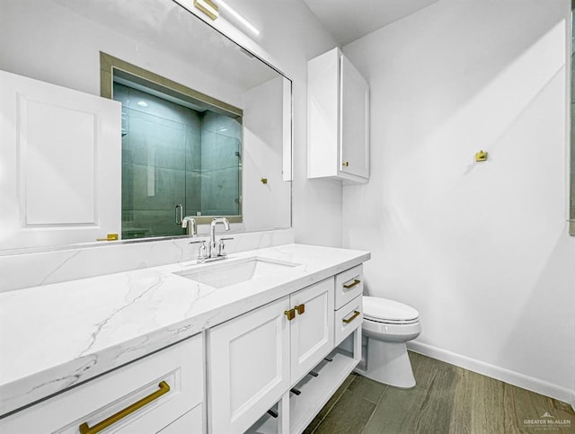 bathroom featuring toilet, wood finished floors, vanity, baseboards, and a shower stall