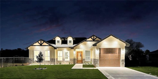 view of front of home with a garage, fence, a yard, concrete driveway, and stone siding